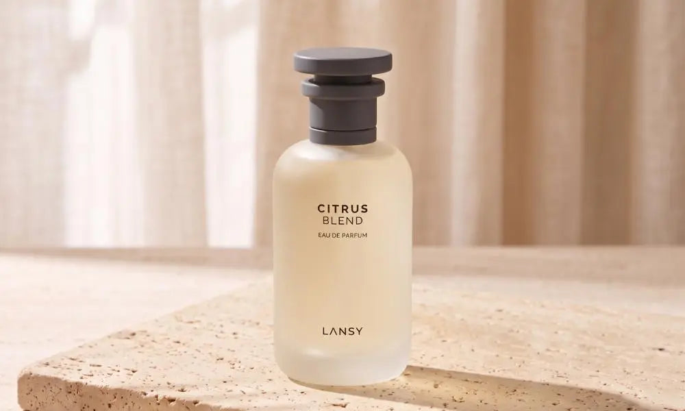 Frosted glass bottle of "Citrus Blend LANSY" perfume on a stone slab