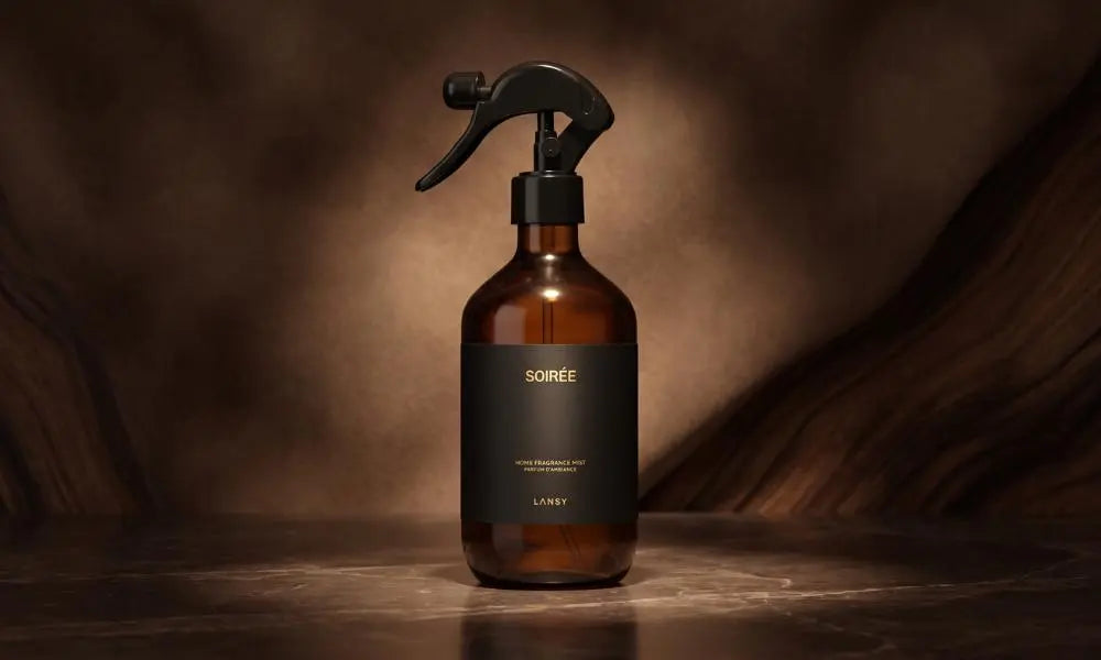 An amber spray bottle labeled 'SOIRÉE' rests centered on dark marble against a textured, moody brown background.