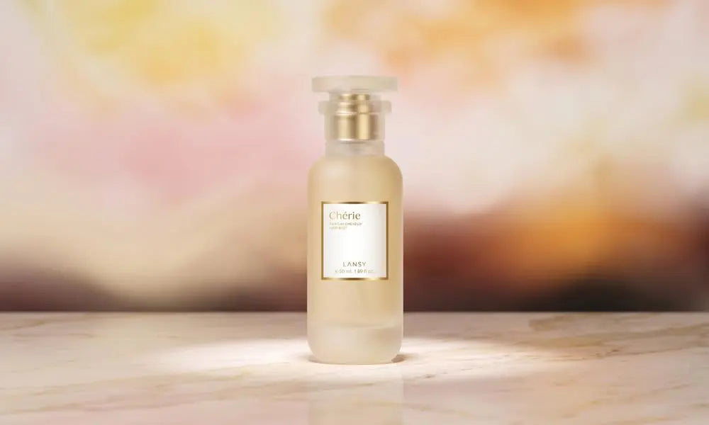 A frosted glass bottle of Chérie perfume by Lansy stands centered on a marble surface, with a soft,