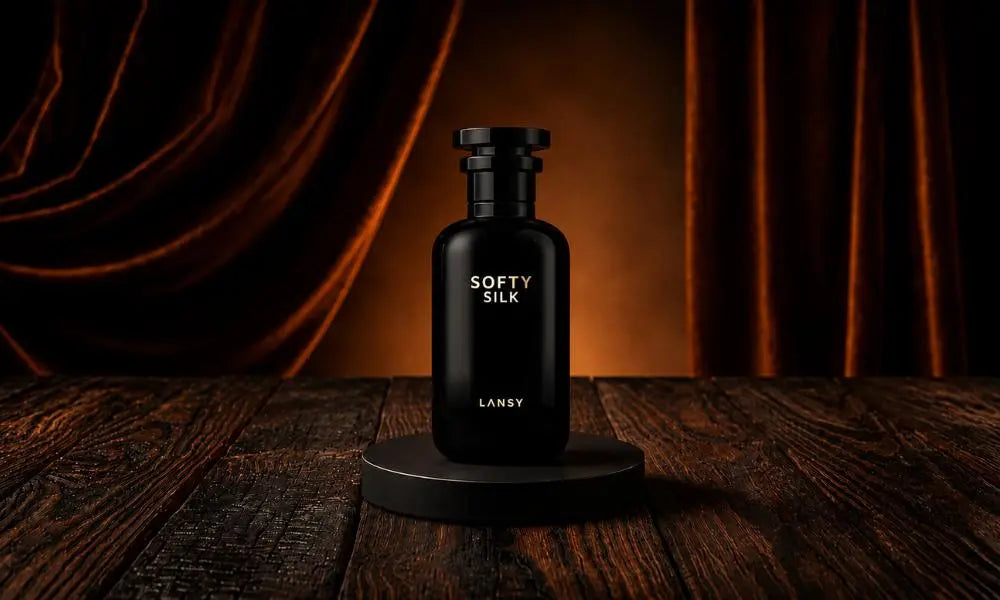 A glossy black perfume bottle labeled "SOFTY SILK LANSY" in gold text, centered on a low black circular display stand on a dark rustic wooden table, set against a background of warm brown draped silk curtains.