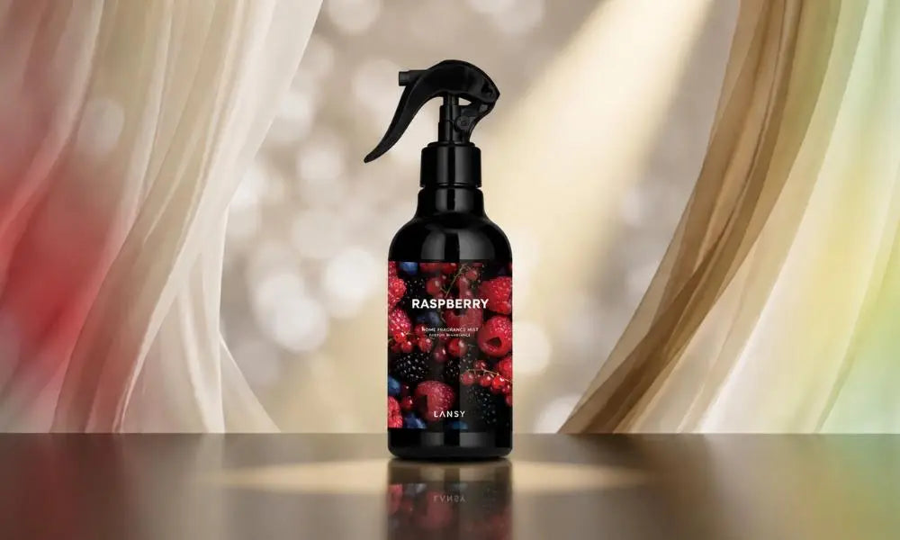 An amber spray bottle labeled 'ROSE GARDEN' sits centered on a light surface against a soft, pink-toned bokeh background.