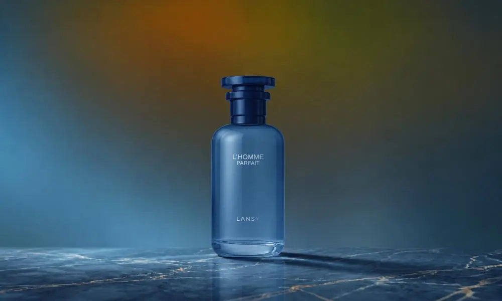 A bottle of "L'HOMME PARFAIT" by Lansy cologne, featuring a semi-translucent blue glass body and a dark blue cap, standing on a blue marble surface with a muted, warm-toned background.