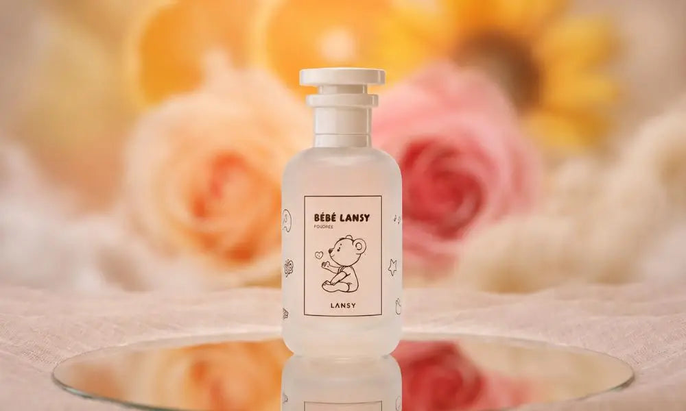 perfume bottle "BÉBÉ LANSY POUDREE" standing on a circular mirror with a soft, blurred background of yellow and pink roses.