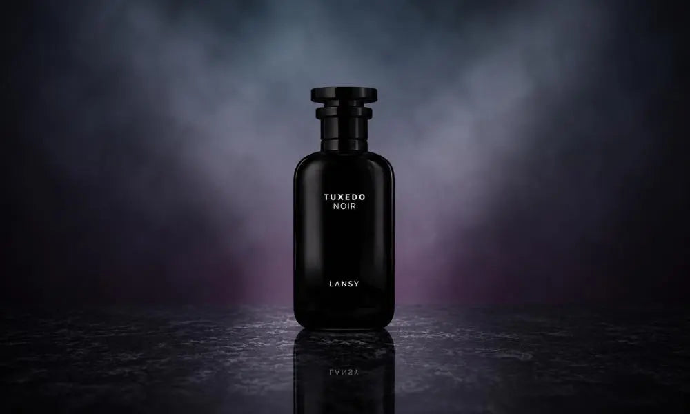 Black glass perfume bottle labeled "TUXEDO NOIR LANSY" standing upright on a reflective dark marble surface against a moody, smoky grey and purple backdrop.