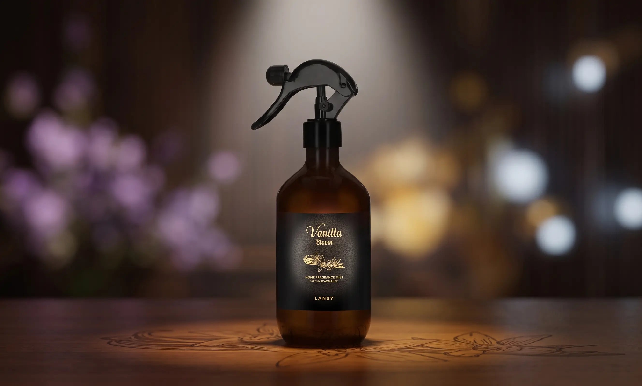 An amber spray bottle labeled "Vanilla Bloom" and "LANSY" sits on an etched wood surface in soft light.