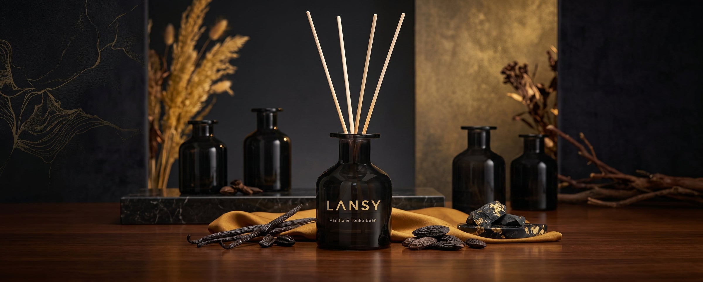 Luxury Lansy Vanilla & Tonka Bean reed diffuser display with dark amber bottle, wooden reeds, vanilla and tonka beans, gold silk accents, dark wood surface, botanicals, and cinematic warm lighting.