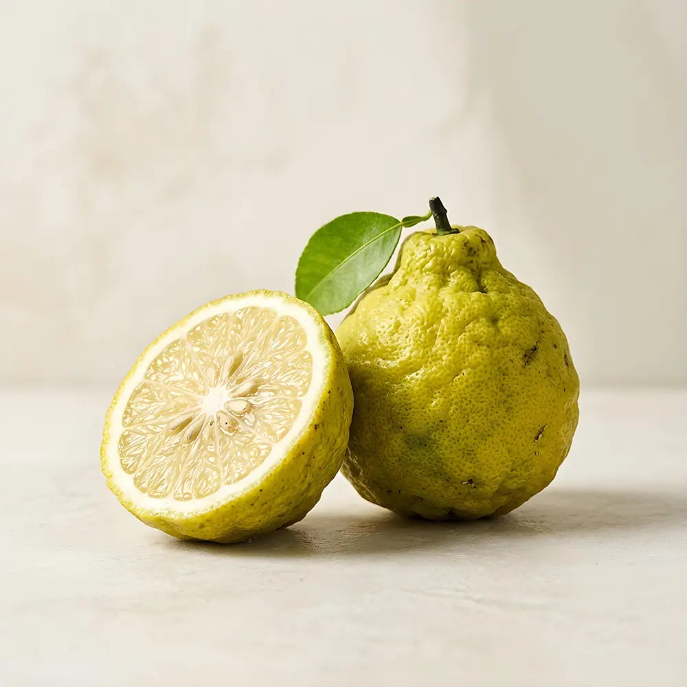 Green fruit, possibly a guava, with a halved version on a light background