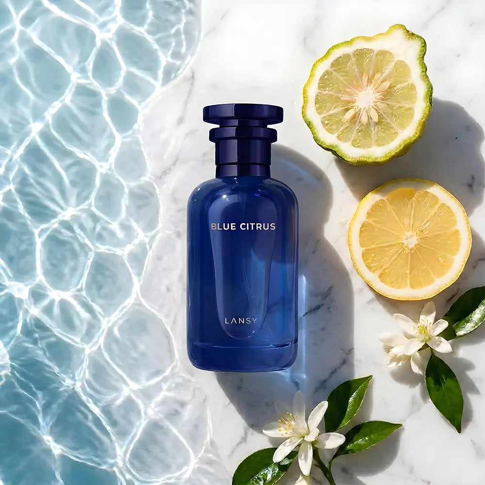 Blue Citrus perfume bottle by Lansy with lemons and flowers on a marble surface.