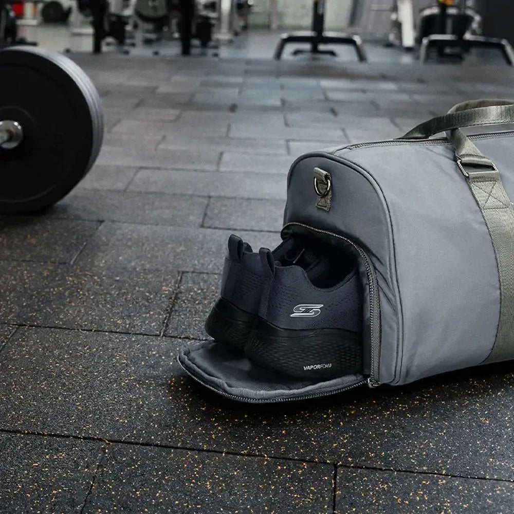 Gray duffel bag with a shoe inside on a gym floor.