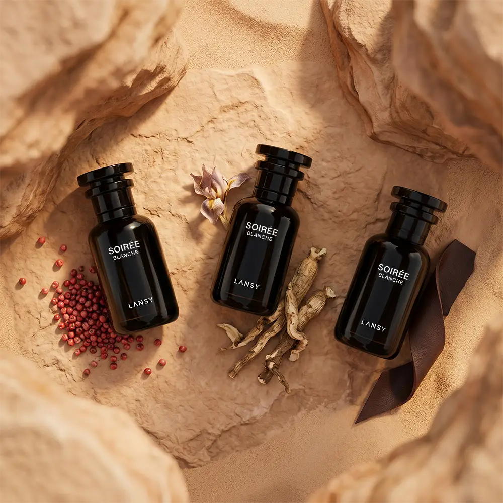 LANSY Soirée Blanche cosmetic bottles with dried roots, red berries and flowers on a sandy surface.
