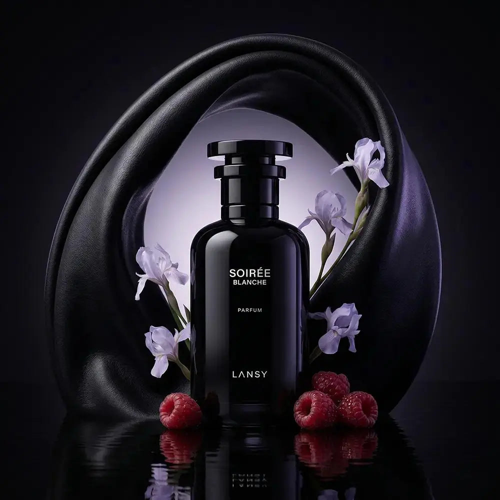 Soirée Blanche Parfum with white irises and red raspberries on a dark reflective background.