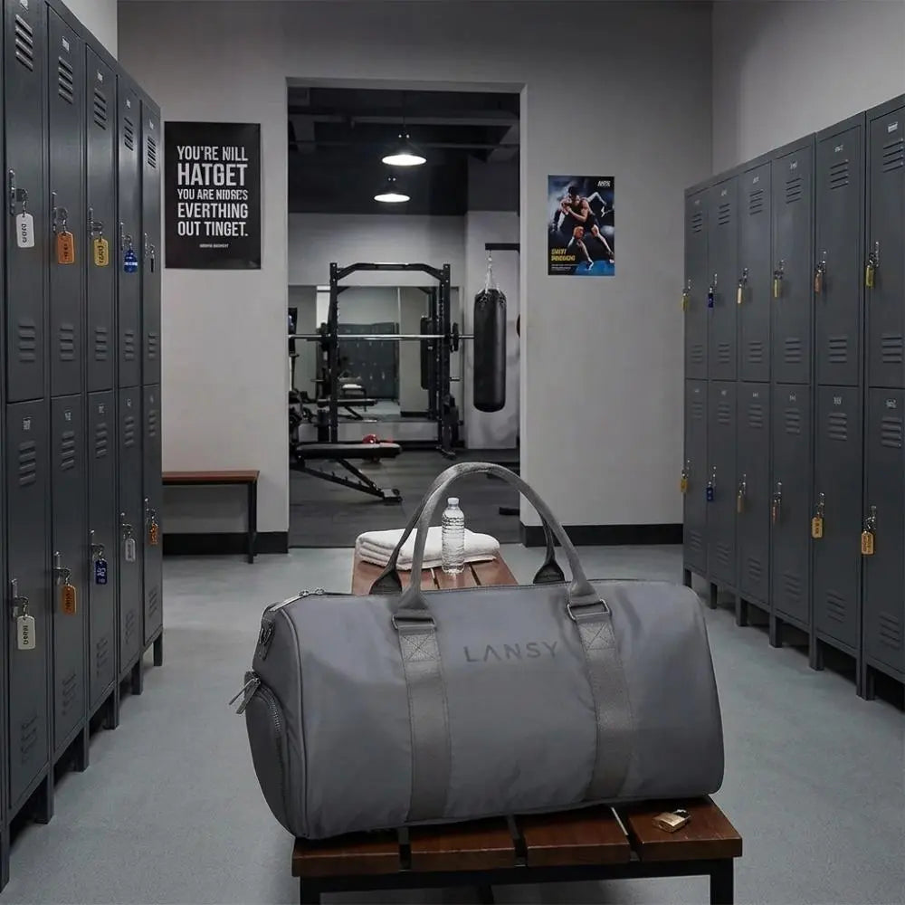 LANSY gray duffel bag on a wooden bench in a modern gym locker room.
