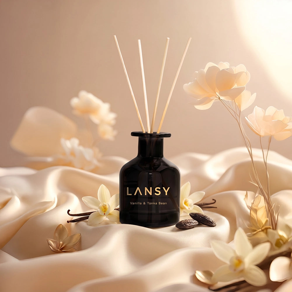 LANSY reed diffuser with pale flowers and vanilla beans on cream satin fabric.