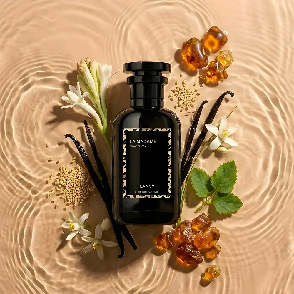 Perfume bottle labeled 'La Madame' by LANSY surrounded by flowers and vanilla beans on a textured beige surface