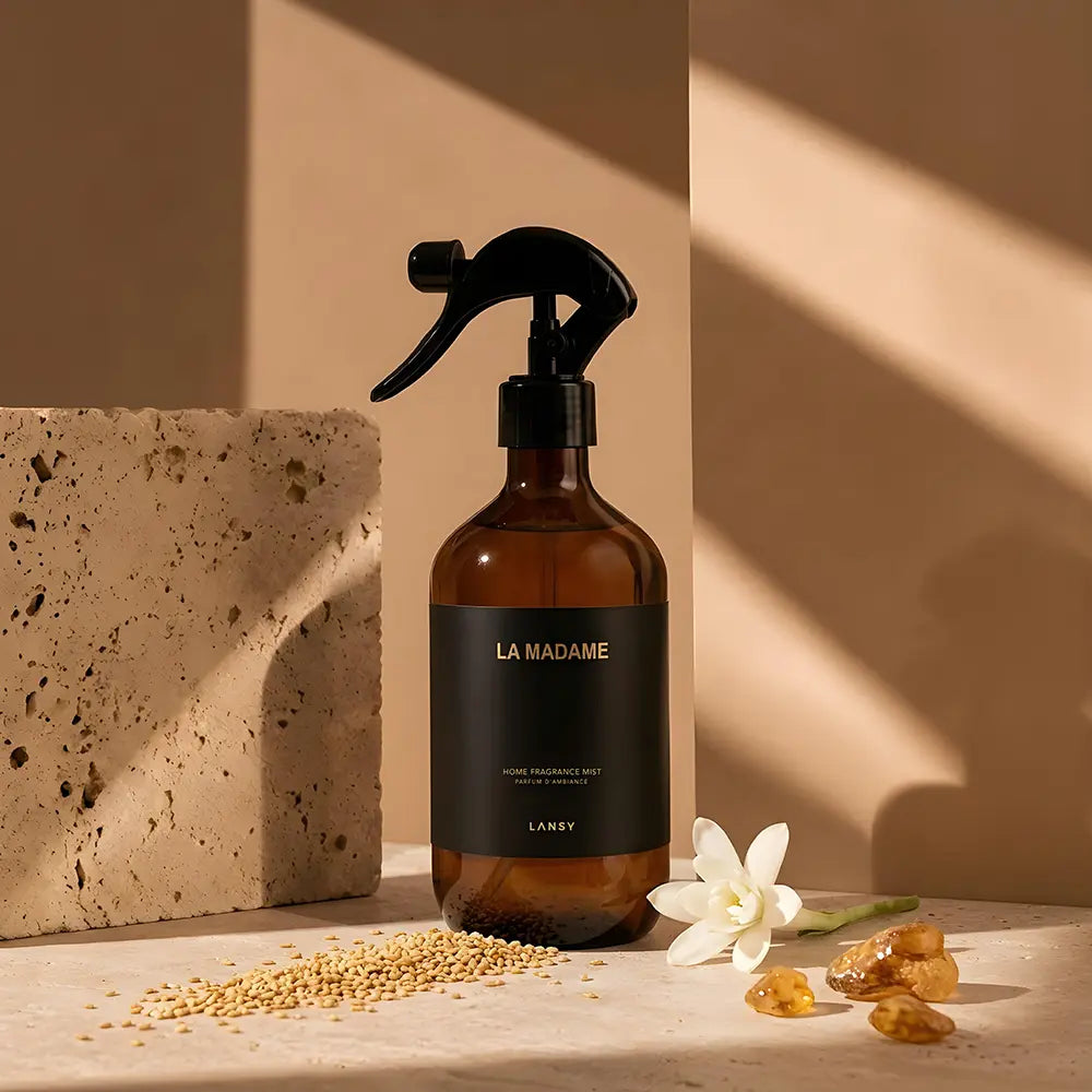 Brown spray bottle labeled 'La Madame' on a beige surface with decorative elements.