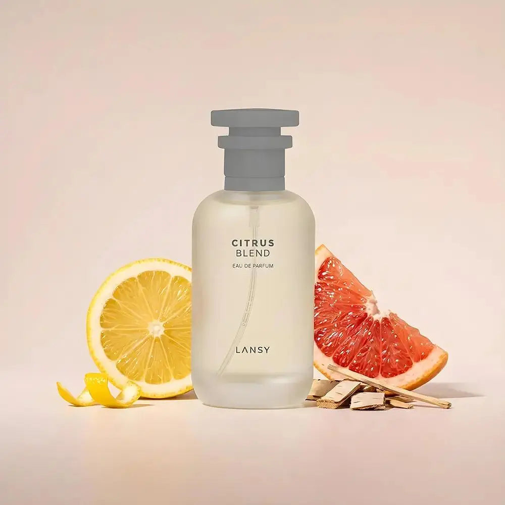LANSY Citrus Blend body wash with lemon, grapefruit and cinnamon sticks on a soft pink background.