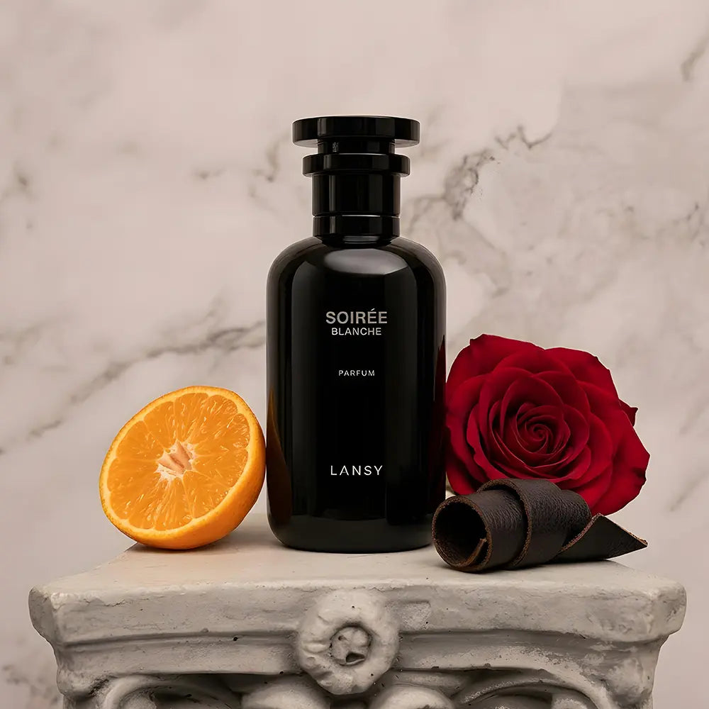 Black LANSY perfume bottle with a red rose and orange on a marble surface